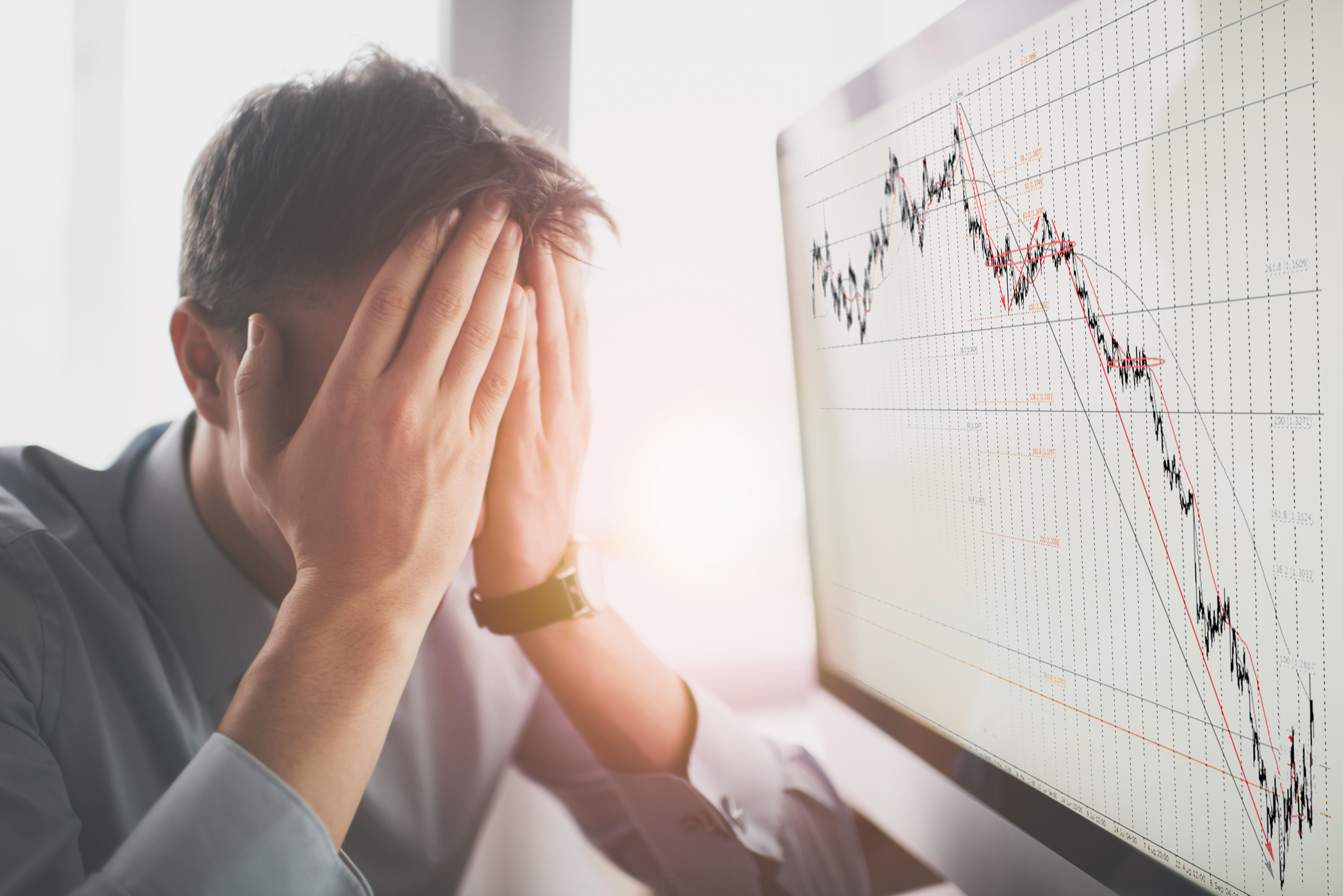 Frustrated stressed shocked business man with financial market chart graphic going down on grey office wall background. Poor economy concept. Face expression, emotion, reaction